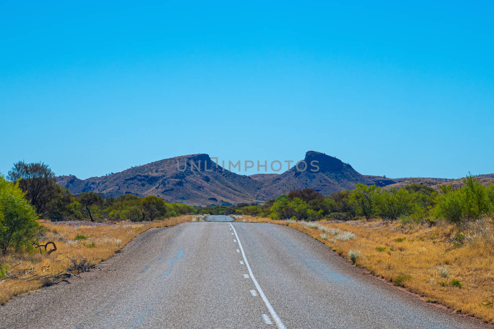 Straight road leading towards gap in between two mountain tops at Karijini National Park Australia