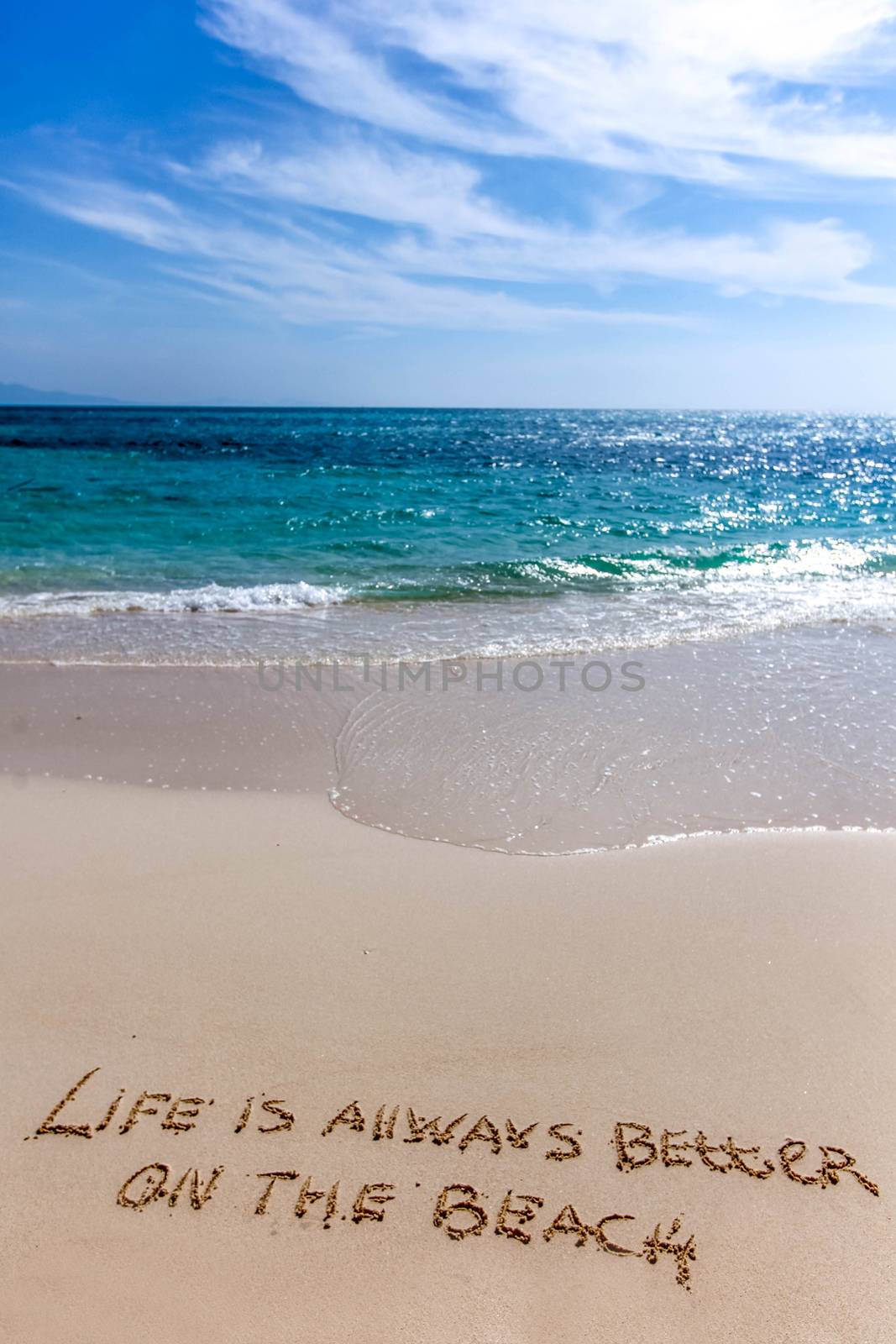 Life is always better on the beach written on the sand of tropical sea beach