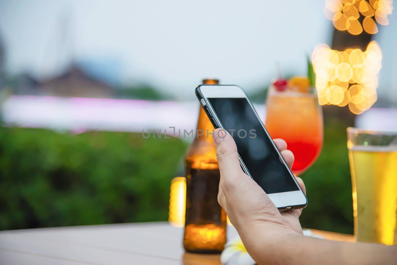 Man using mobile during happy time relax in restaurant with softdrink and green garden background by pairhandmade