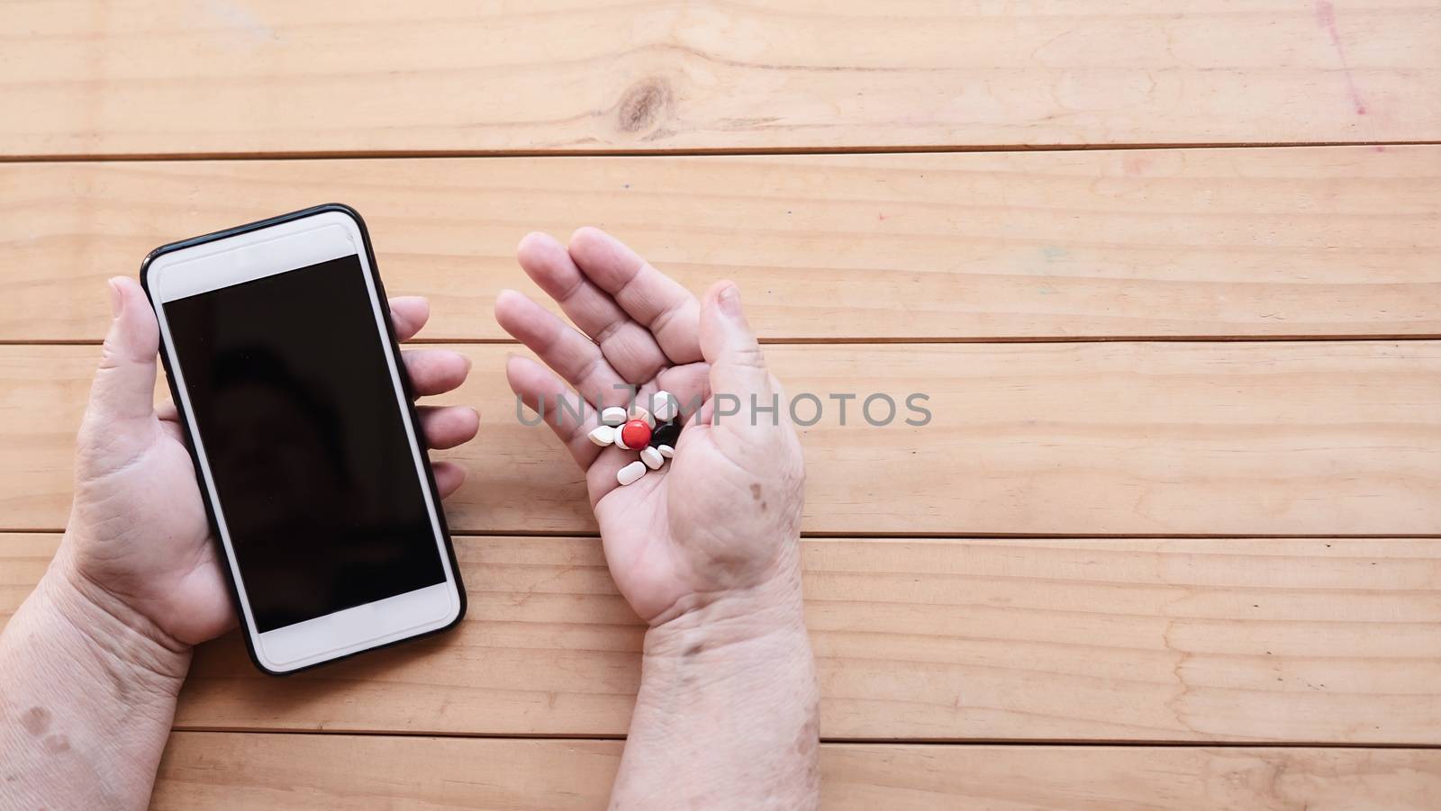 Old lady holding medicine tablet and mobile phone - people with medical schedule manage health care using technology concept