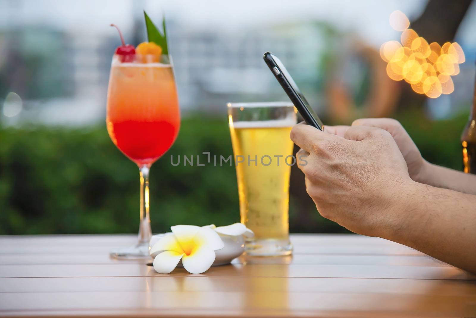 Man using mobile during happy time relax in restaurant with softdrink and green garden background by pairhandmade