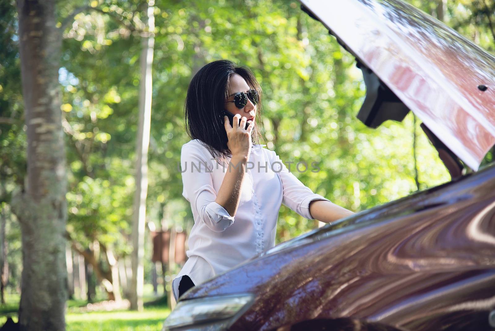 Asian woman calling repairman or insurance staff to fix a car engine problem on a local road by pairhandmade
