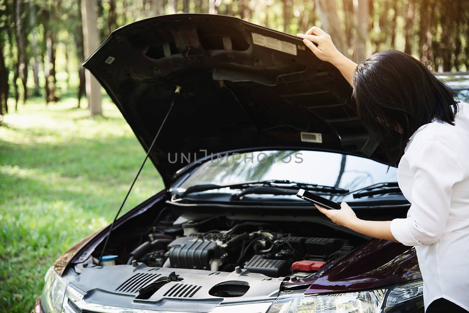 Asian woman calling repairman or insurance staff to fix a car engine problem on a local road - people with car problem transportation concept