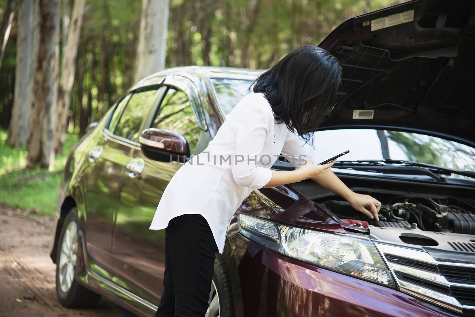 Asian woman calling repairman or insurance staff to fix a car engine problem on a local road - people with car problem transportation concept 