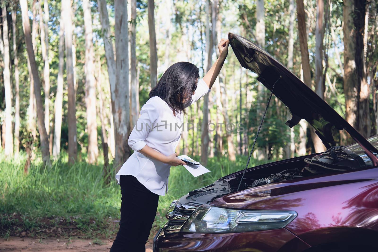 Asian woman calling repairman or insurance staff to fix a car engine problem on a local road - people with car problem transportation concept 