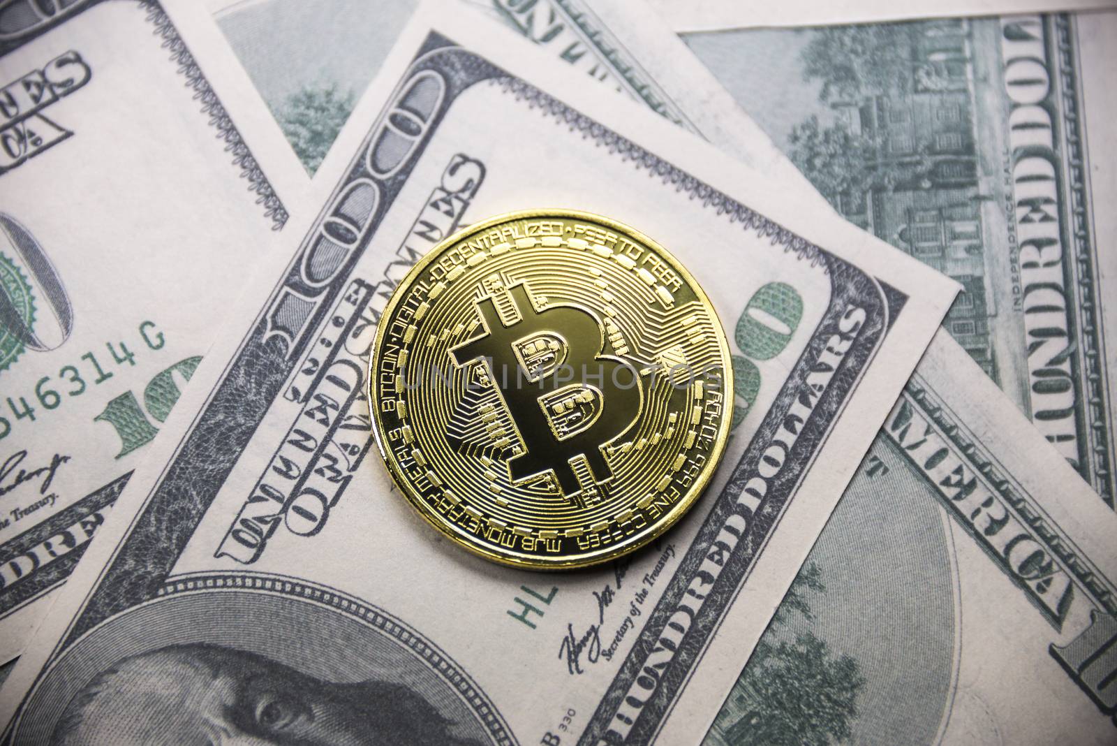 Gold coin Bitcoin on the background of hundred dollar bills.