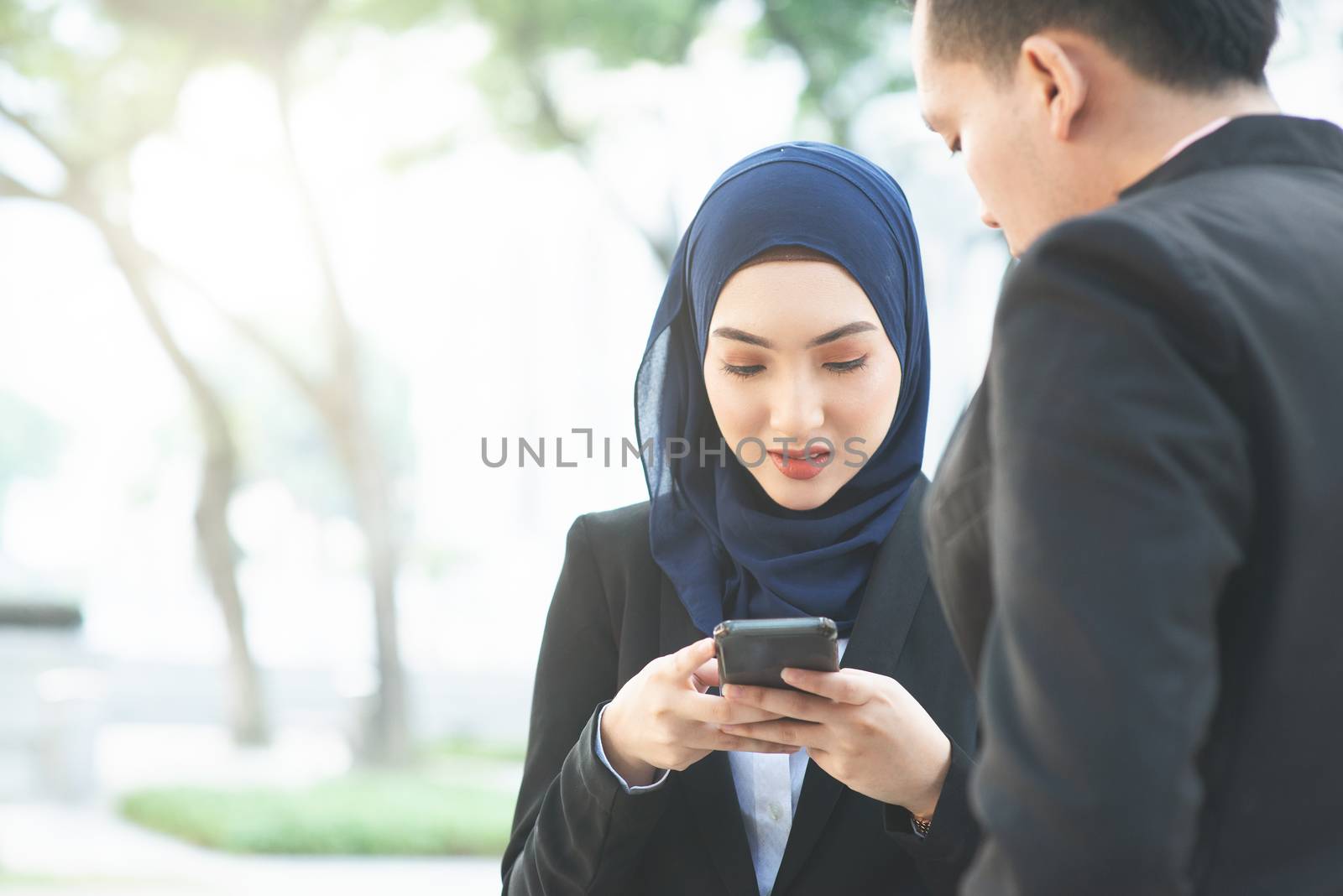 Muslim business women using mobile phone outdoor.