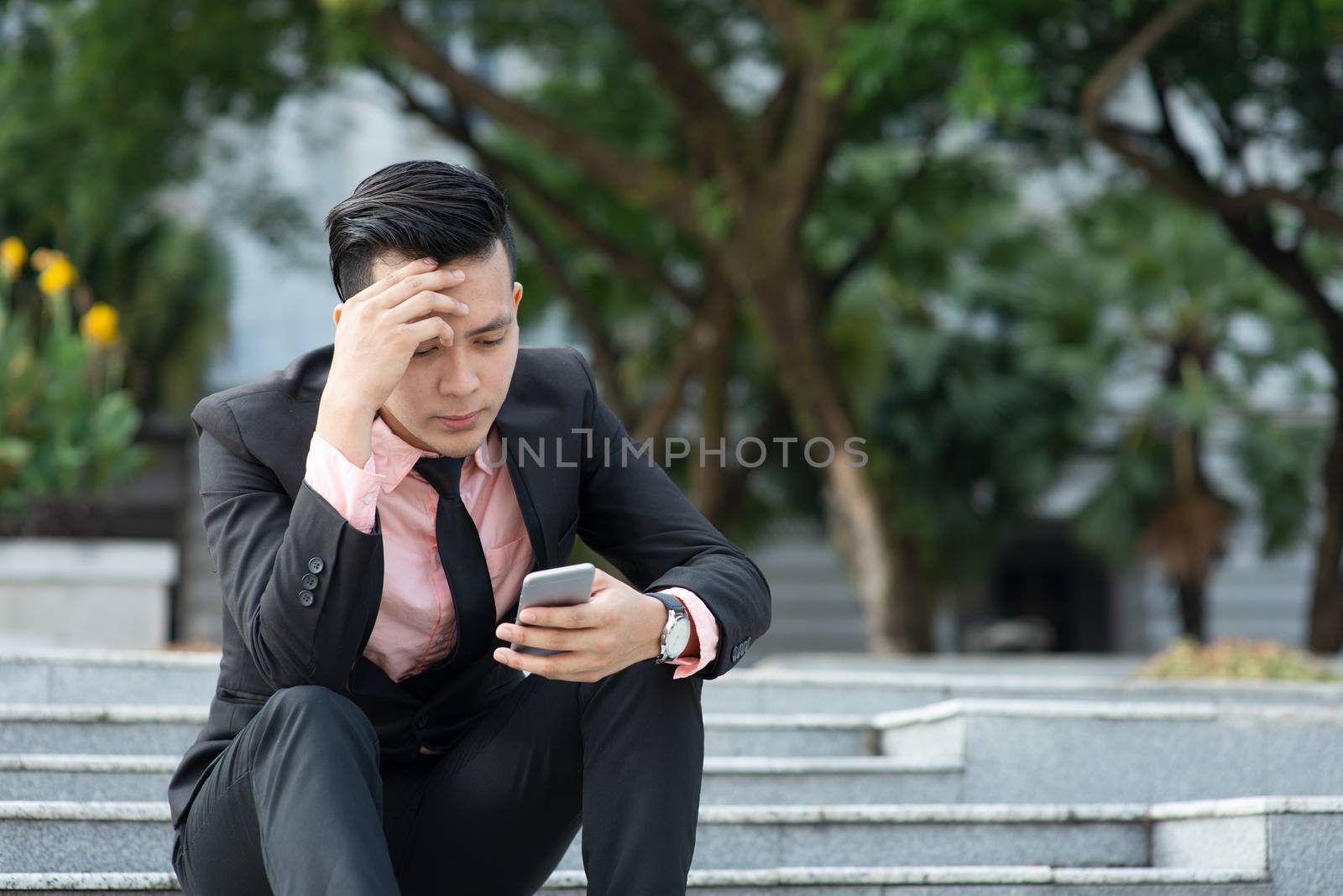 Man looking at mobile phone with serious face, negative emotion, phishing scams concept.