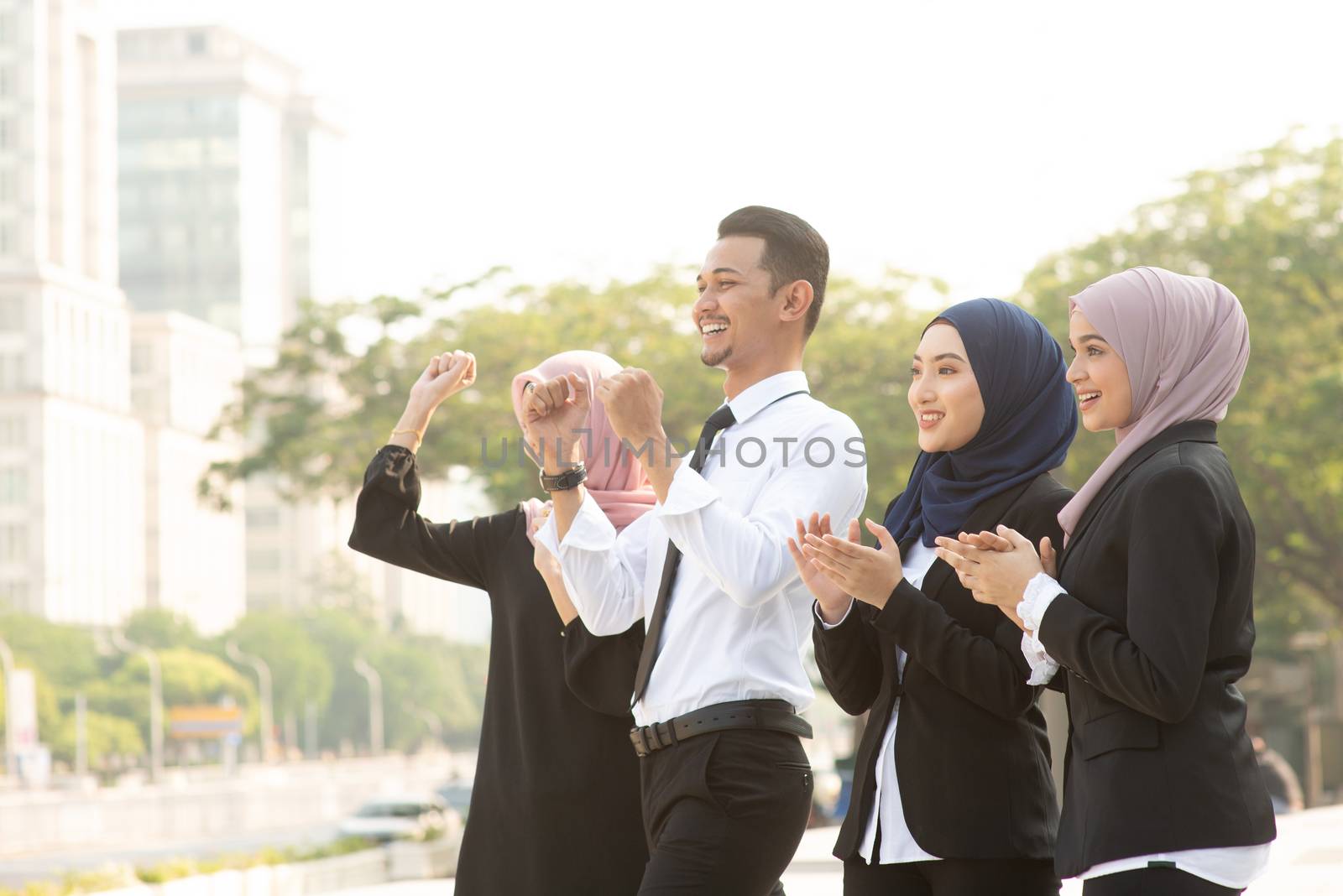 Group of Muslim business people cheering outdoor.