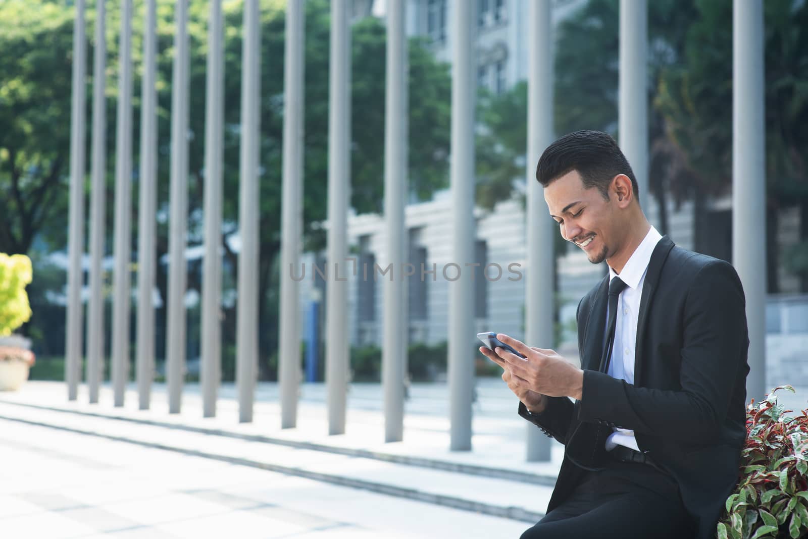 Businessman using mobile phone outdoor during office hour.