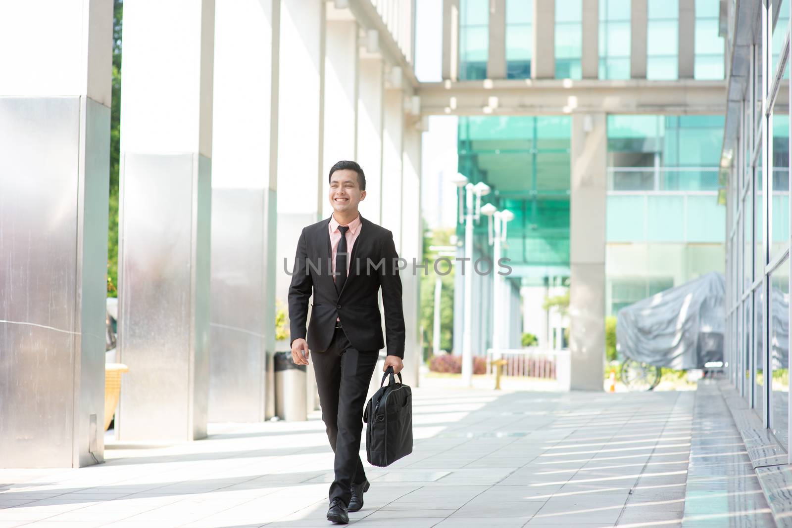 Businessman with suitcase walking outside office building. 