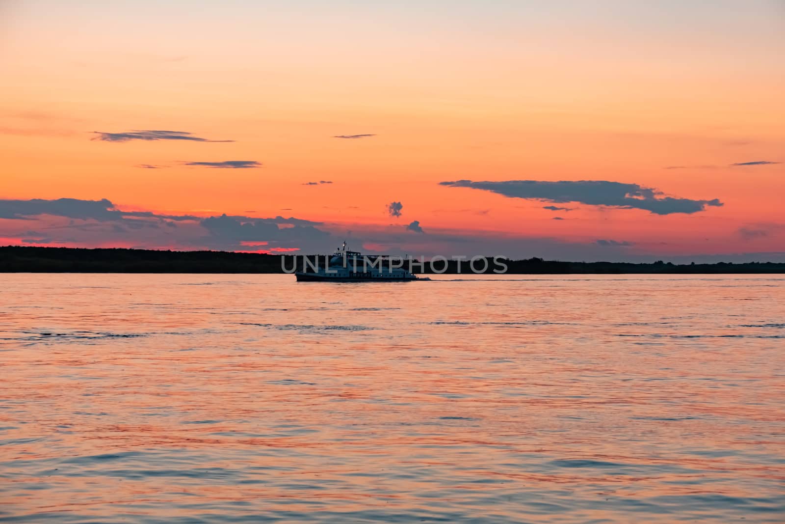 Sunset on the embankment of the Amur river in Khabarovsk. The sun set over the horizon. The embankment is lit by lanterns.