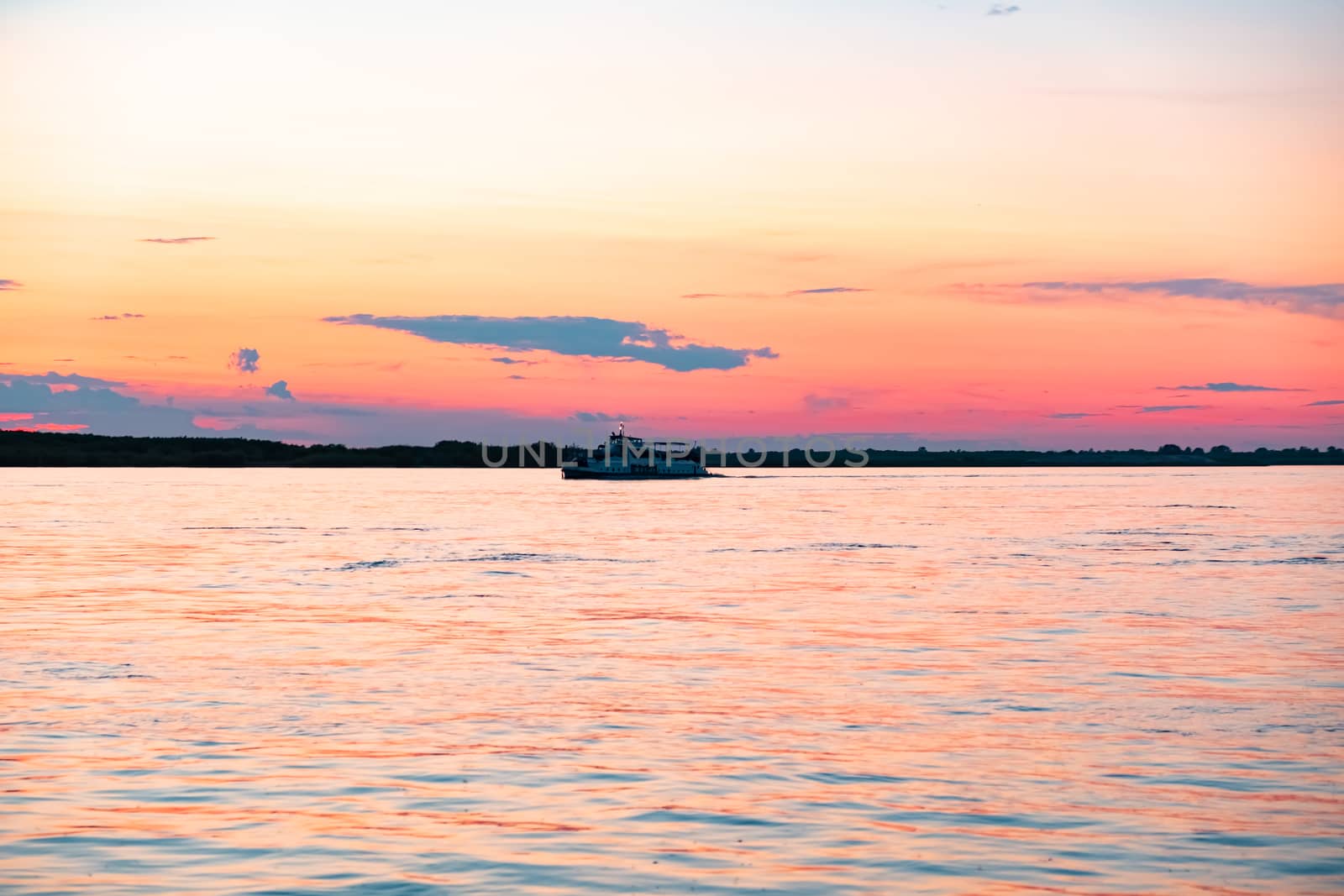 Sunset on the embankment of the Amur river in Khabarovsk. The sun set over the horizon. The embankment is lit by lanterns.