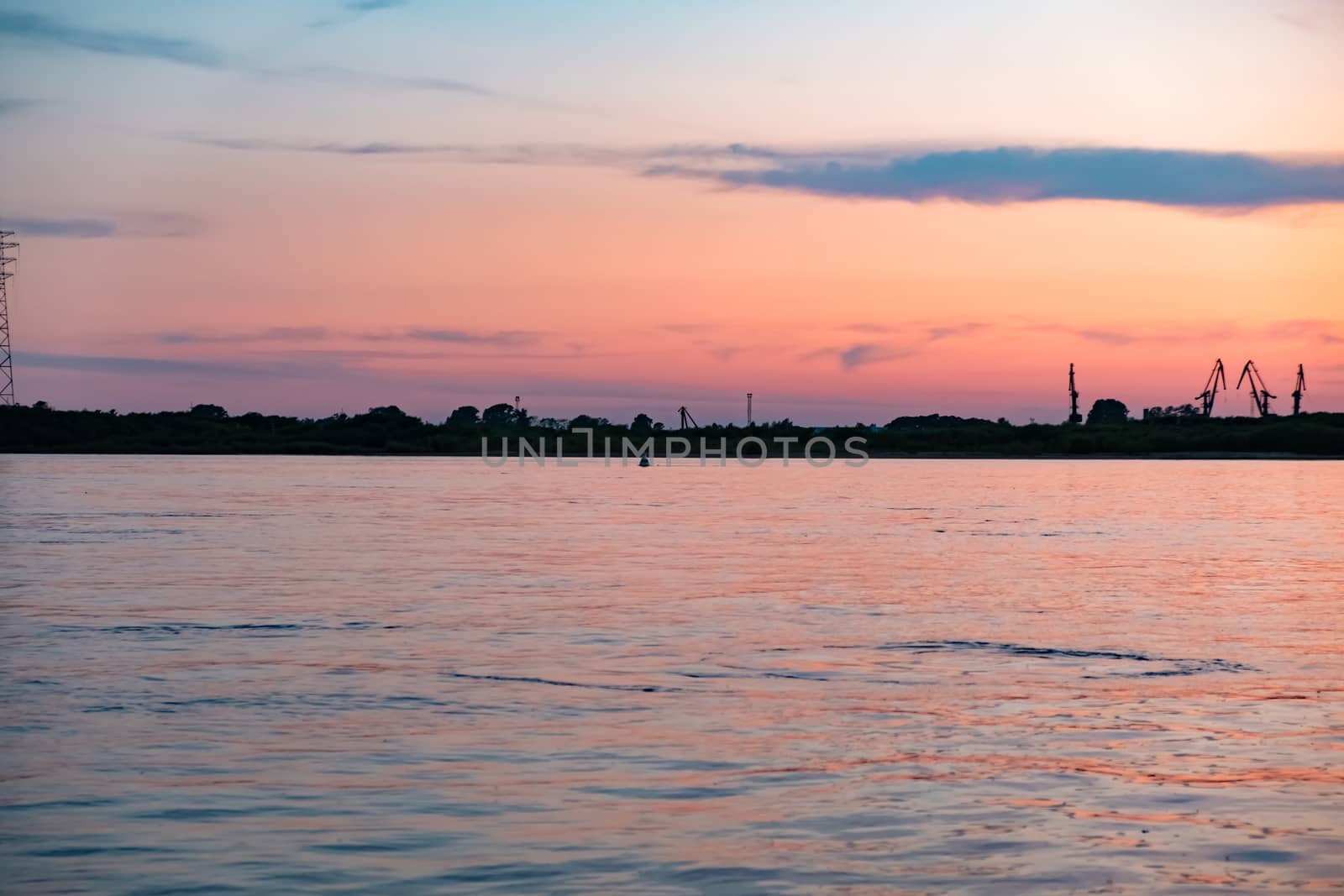 Sunset on the embankment of the Amur river in Khabarovsk. The sun set over the horizon. The embankment is lit by lanterns.