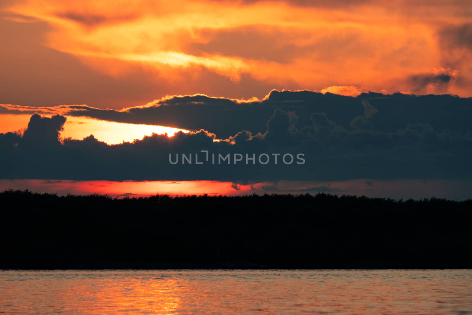 Sunset on the embankment of the Amur river in Khabarovsk. The sun set over the horizon. The embankment is lit by lanterns.