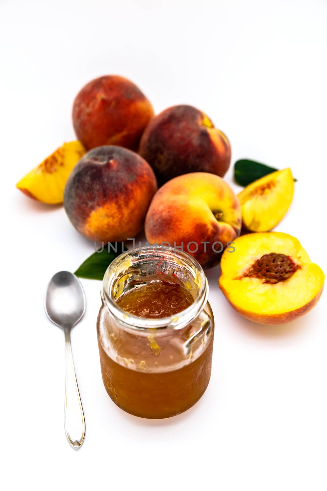 Composition of a bunch of peaches with a jar of jam on a white background