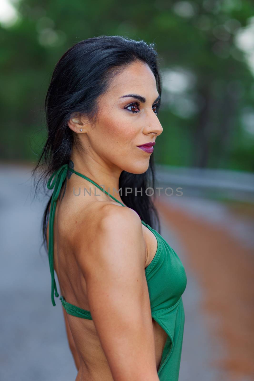 Fitness girl posing in the beach forest with a beautiful green swimsuit