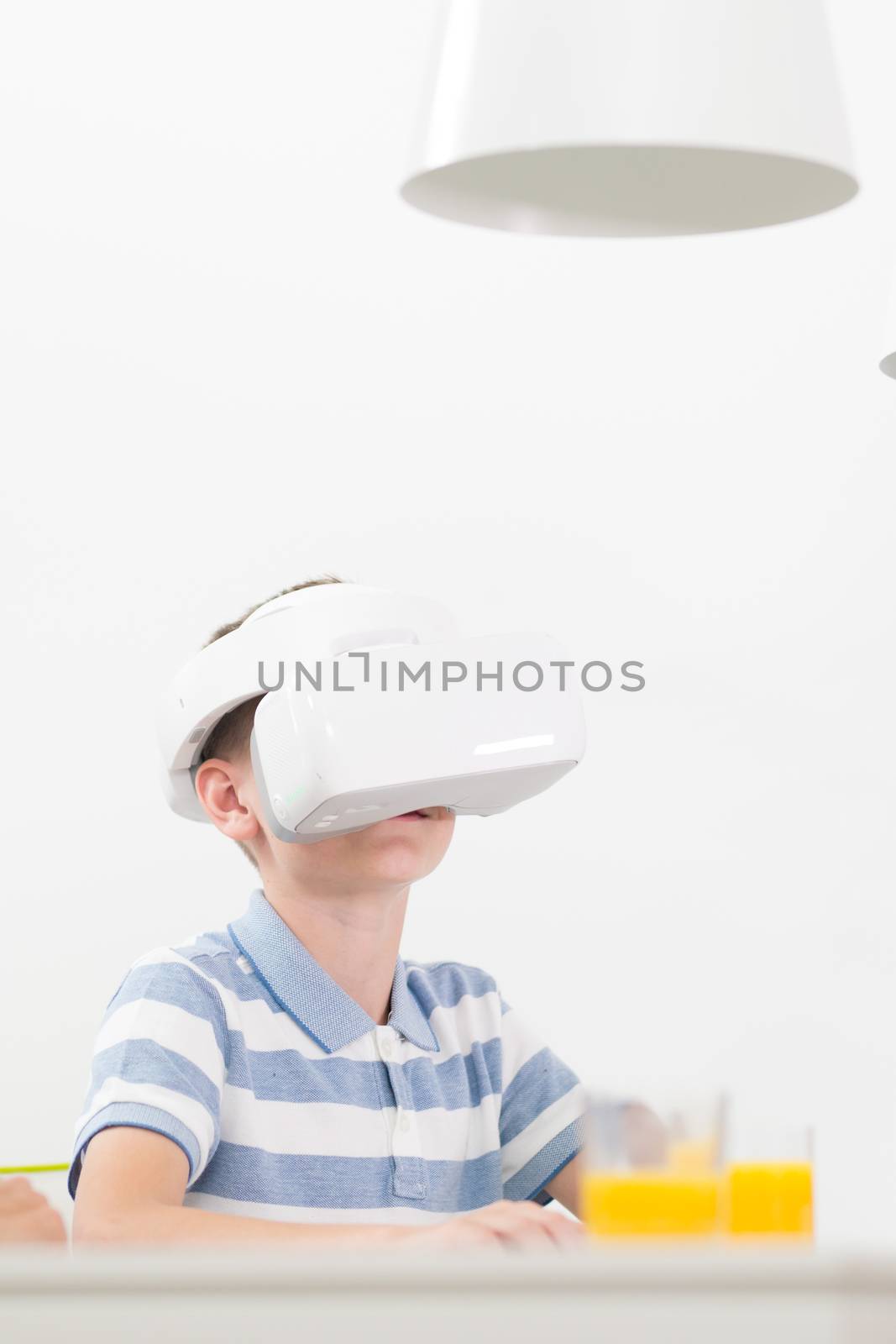 Amazed child using virtual reality headsets while sitting at the dinner table. by kasto
