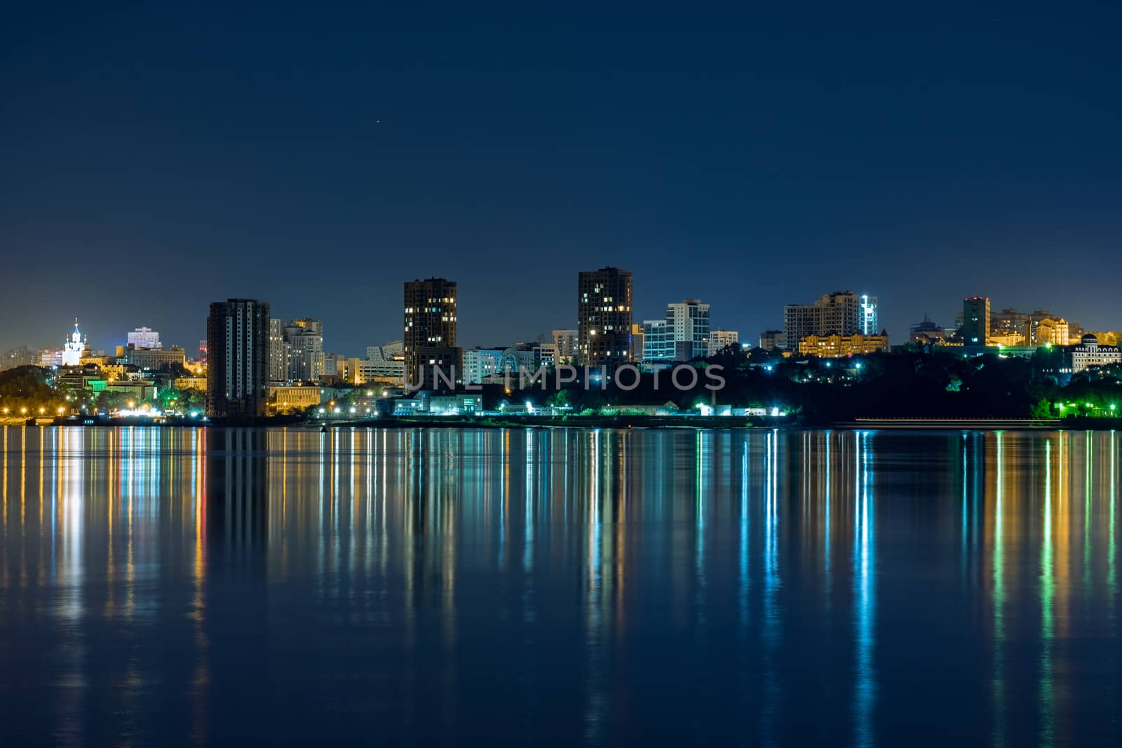 Night View of the city of Khabarovsk from the Amur river. Blue night sky. The night city is brightly lit with lanterns