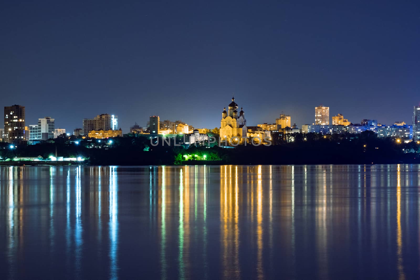 Night View of the city of Khabarovsk from the Amur river. Blue night sky. The night city is brightly lit with lanterns