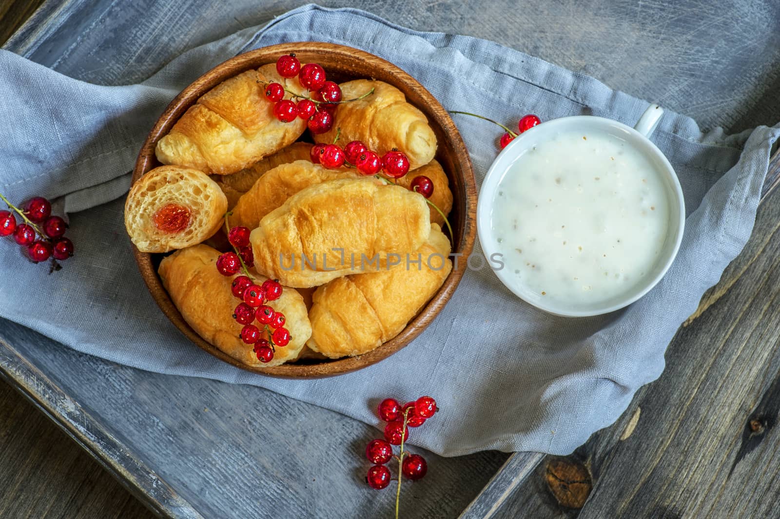 Croissants with currant berries on a wooden tray. The concept of a wholesome breakfast