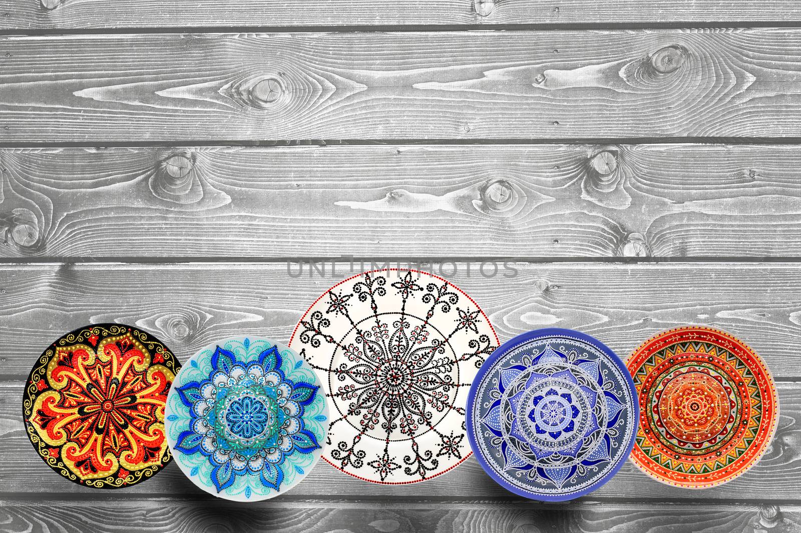 Set of decorative ceramic plates hand-painted with acrylic paints on a wooden background with place for text