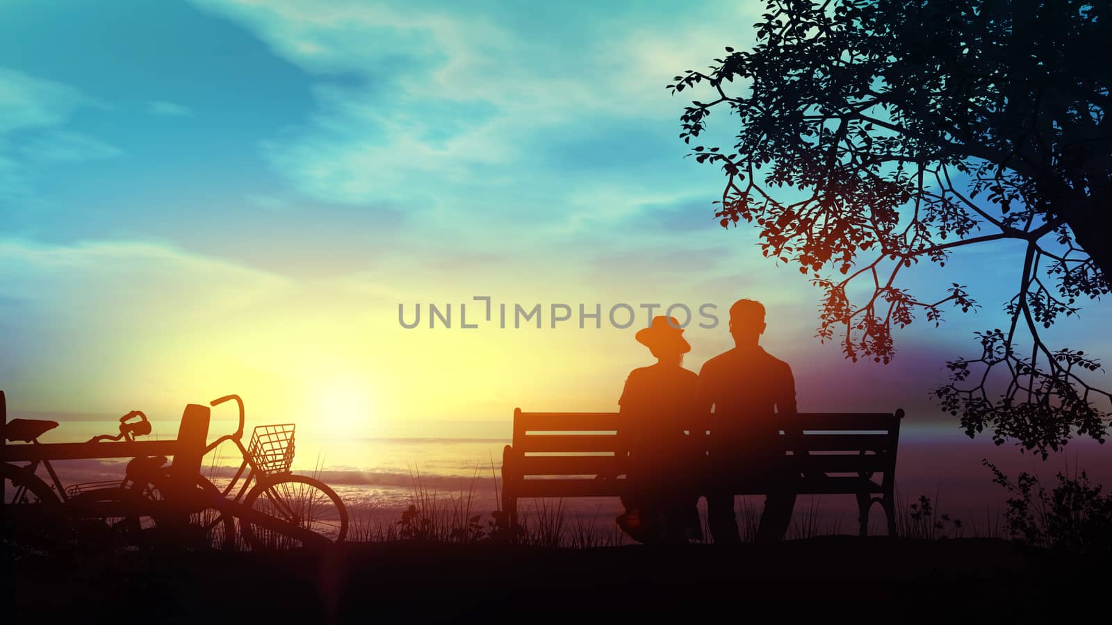 Silhouettes of a couple sitting on a bench and looking at the setting sun over the ocean.