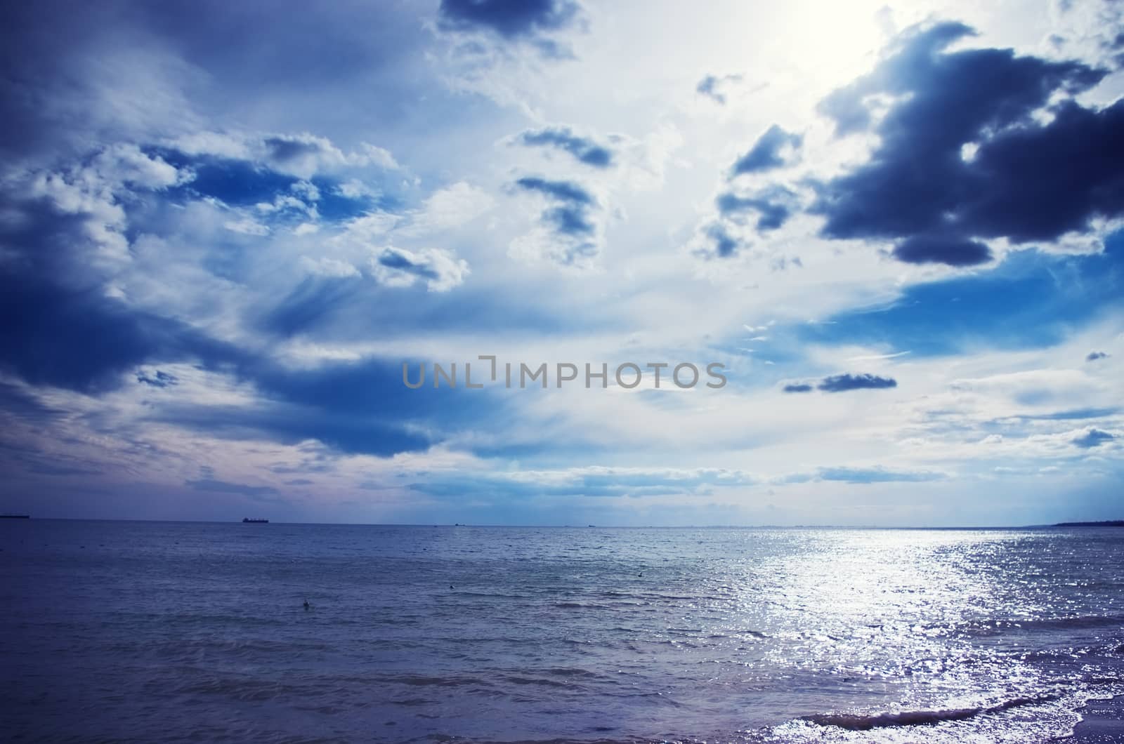 Cloudy blue sky above a blue surface of the sea