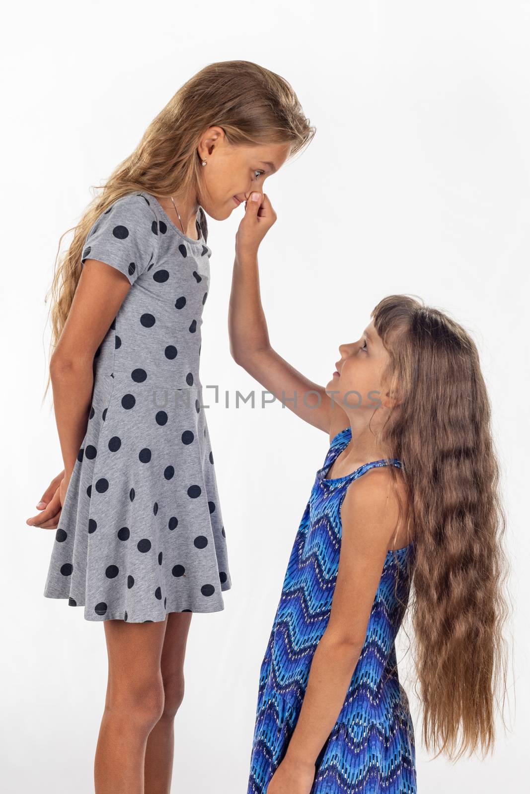Two girls, one stood on a chair and the other holds the first by the nose