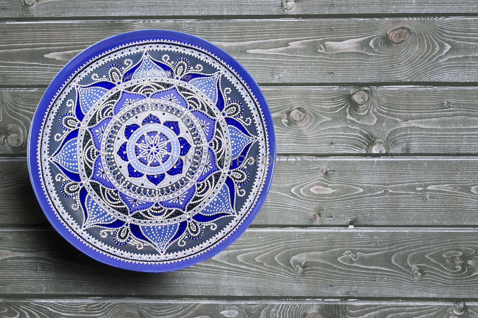 Set of decorative ceramic plates hand painted dot pattern with acrylic paints on a gray wooden background. Copy space