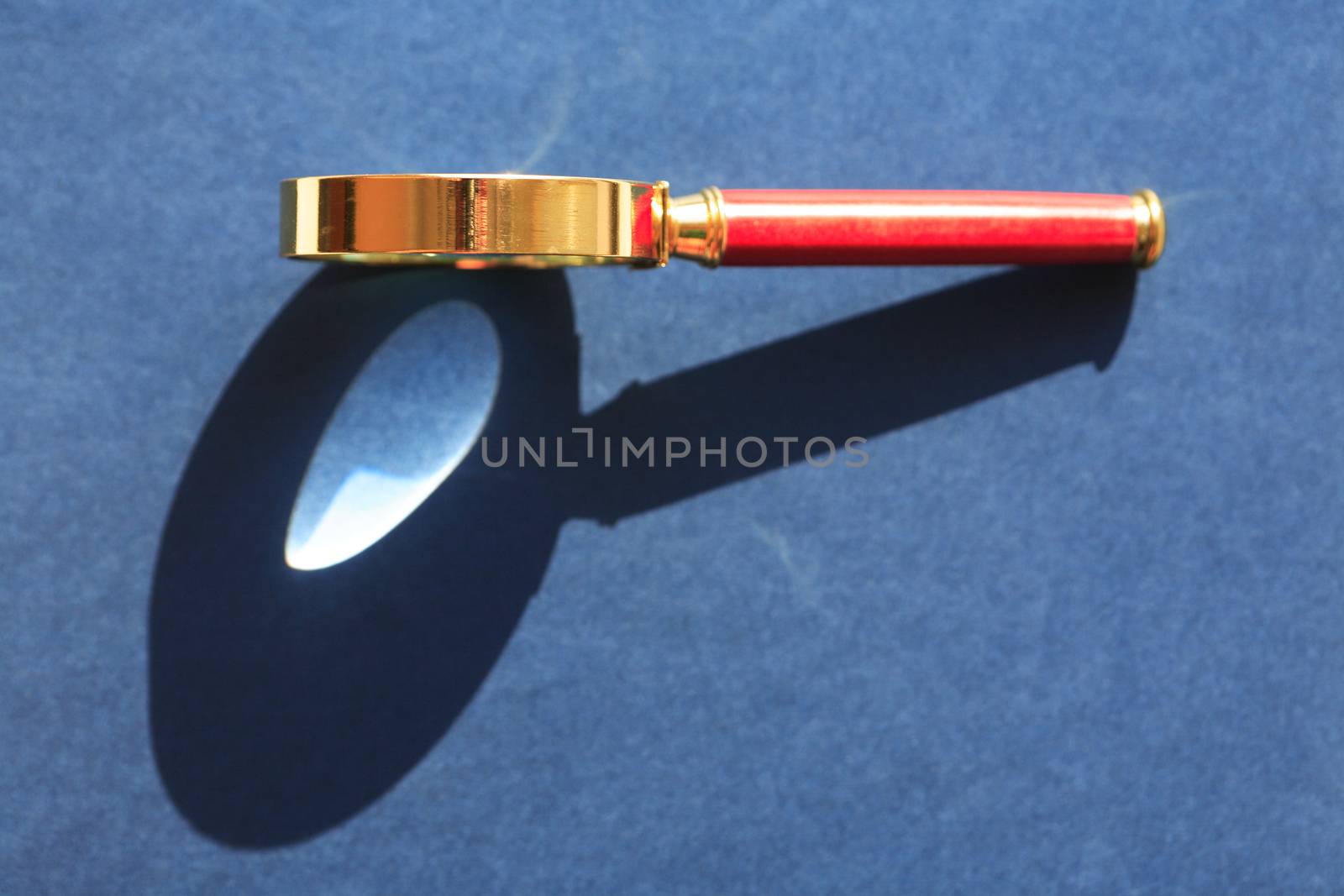 Nice retro magnifying glass under sunlight on gray background