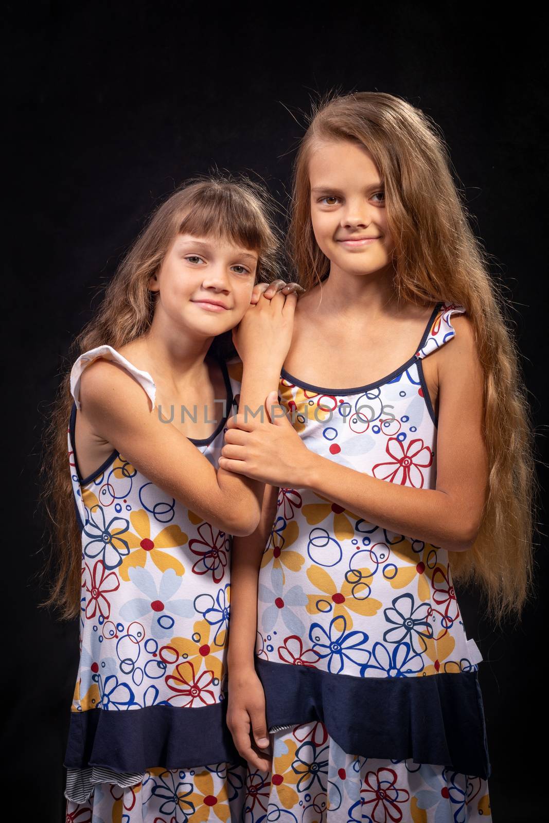 Two sisters of different ages on a black background