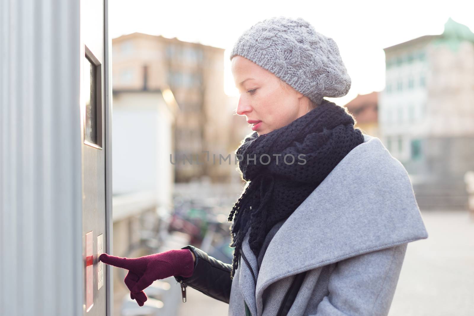 Casual woman buying public transport tickets on city urban vedning machine on cold winter day. by kasto
