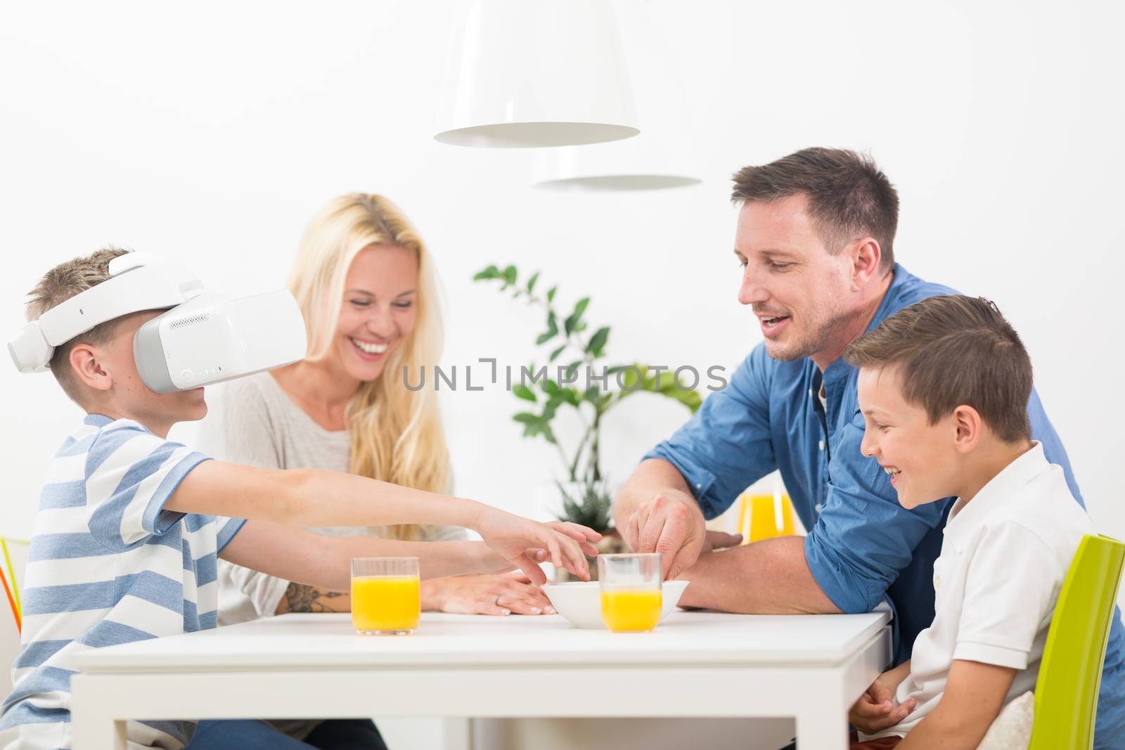 Happy caucasian family at home on living room sofa having fun playing games using virtual reality headset.