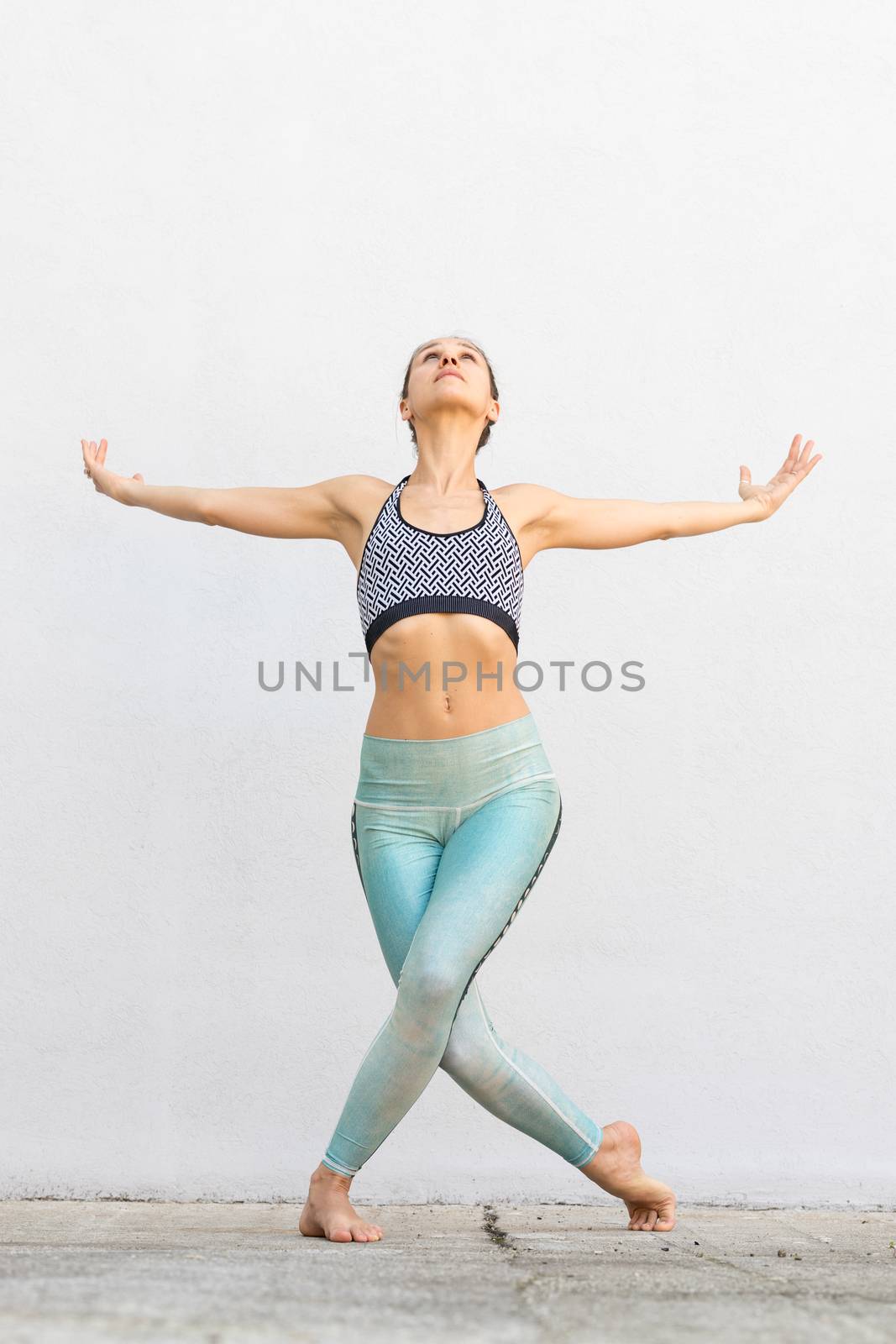 Fit sporty active girl in fashion sportswear doing yoga fitness exercise in front of gray wall, outdoor sports, urban style.