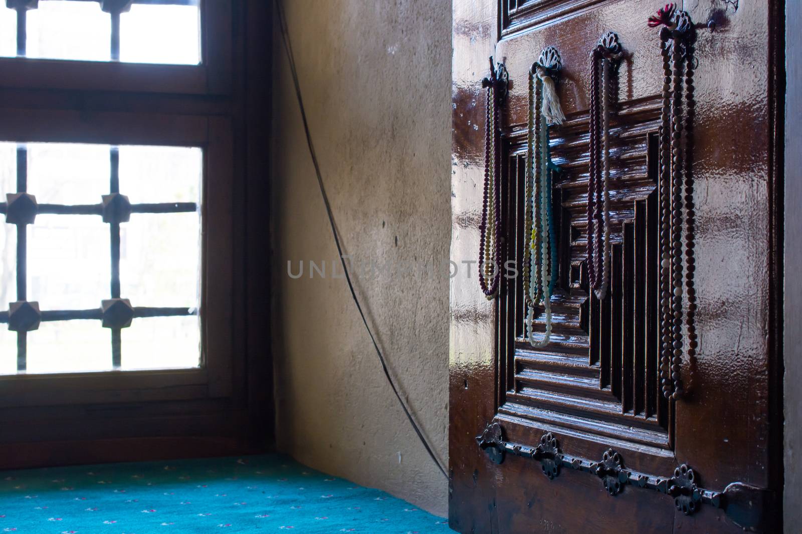 light and rosary reflected in the window of the mosque