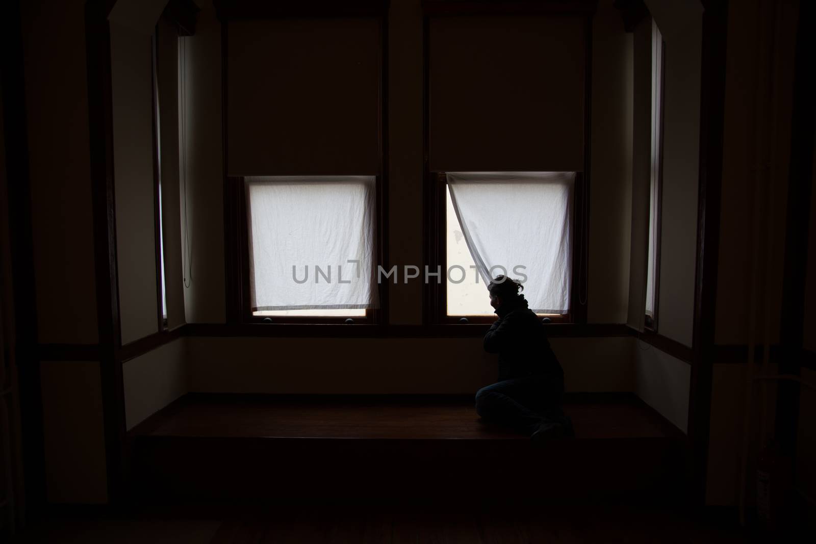 The young, beautiful woman in the dark room. She looks out of the window.