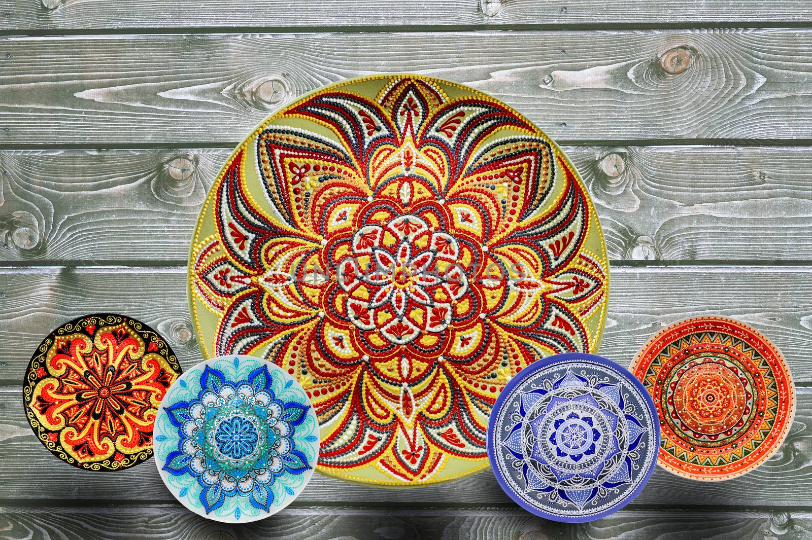 Set of decorative ceramic plates hand painted dot pattern with acrylic paints on a gray wooden background. Copy space