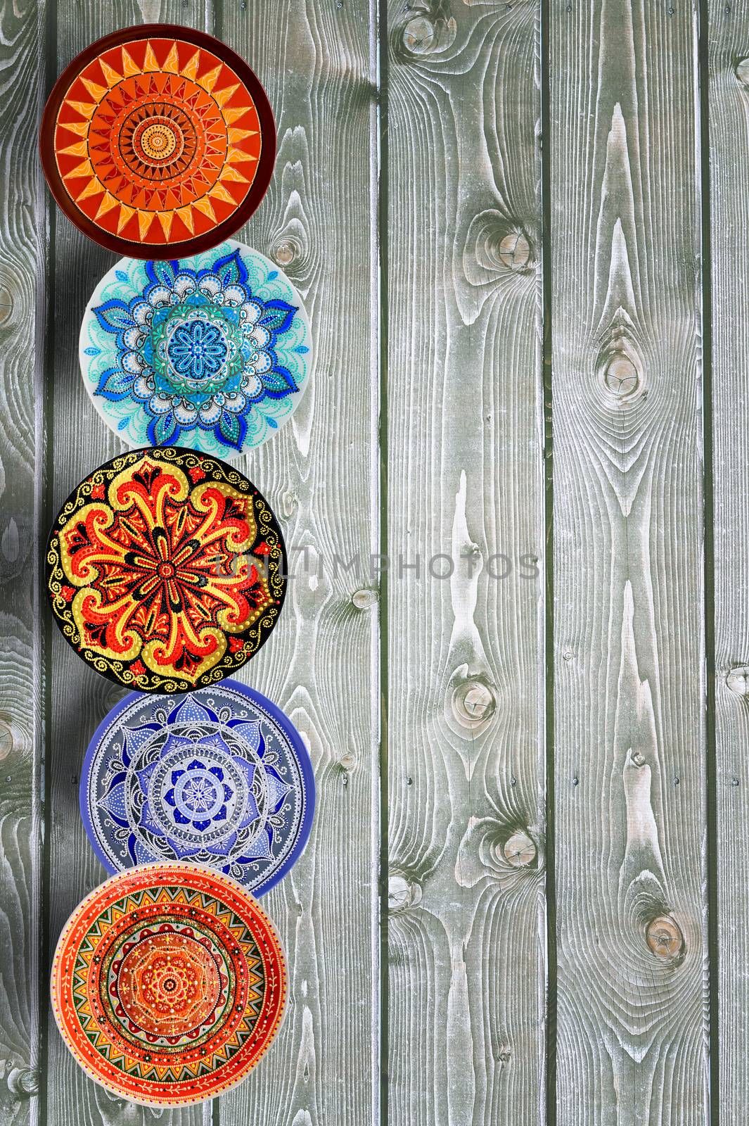 Vertical Set of decorative ceramic plates hand painted dot pattern with acrylic paints on a gray wooden background. Copy space