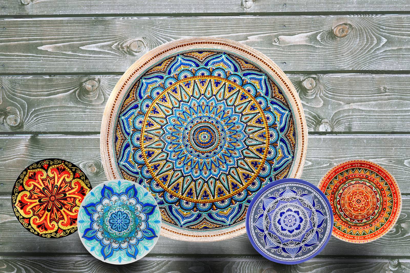 Set of decorative ceramic plates hand painted dot pattern with acrylic paints on a gray wooden background. Copy space