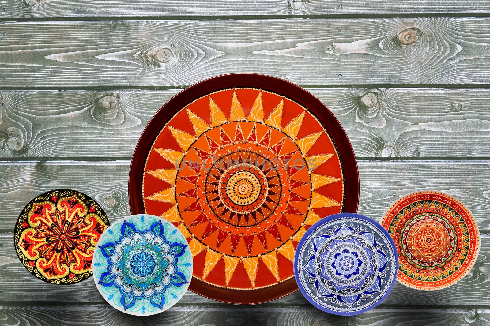 Set of decorative ceramic plates hand painted dot pattern with acrylic paints on a gray wooden background. Copy space