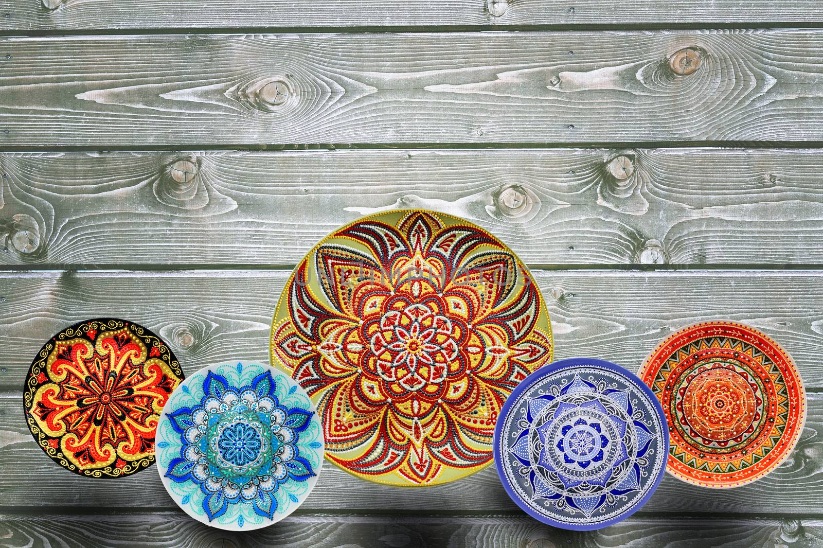 Set of decorative ceramic plates hand painted dot pattern with acrylic paints on a gray wooden background. Copy space