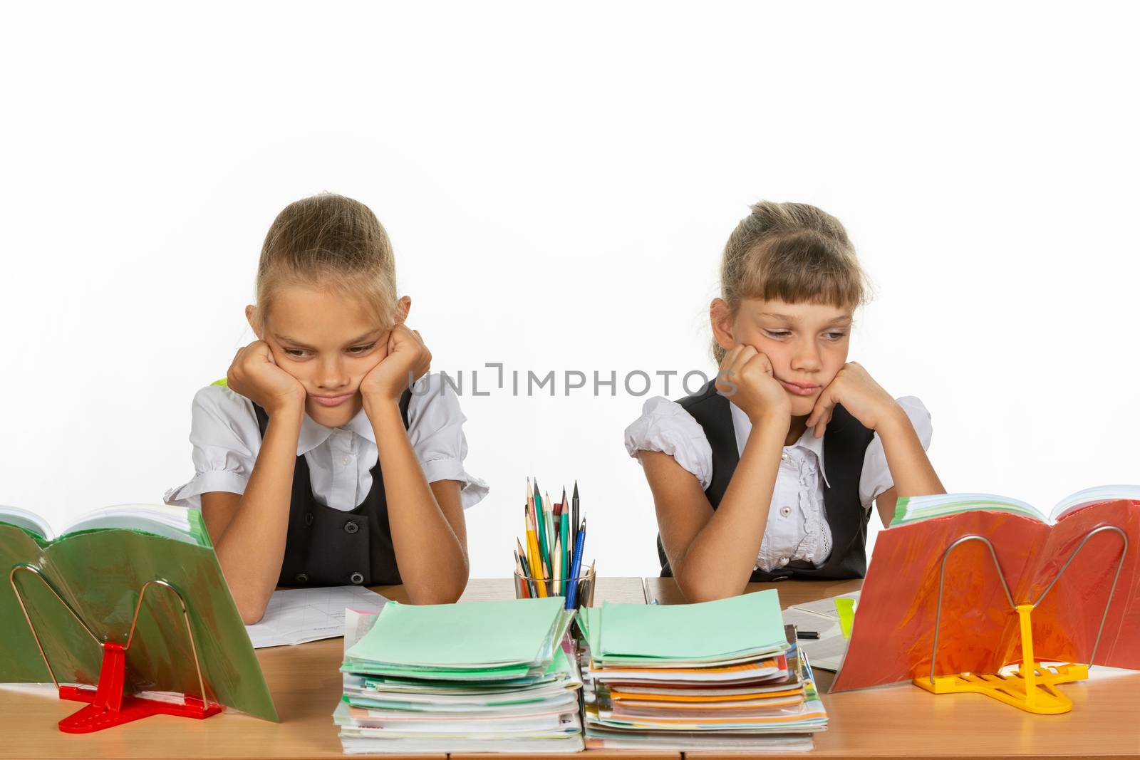 Sad schoolgirls look at textbooks in class