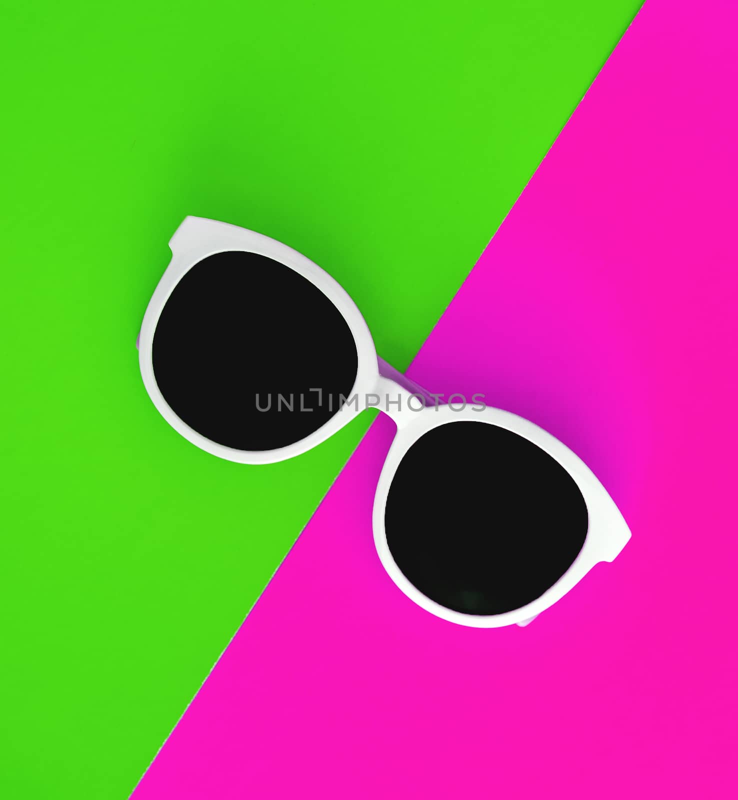 Sunny stylish white sunglasses on a bright green-cyan and crimson-pink background, top view, isolated. Copy space. Flat lay.