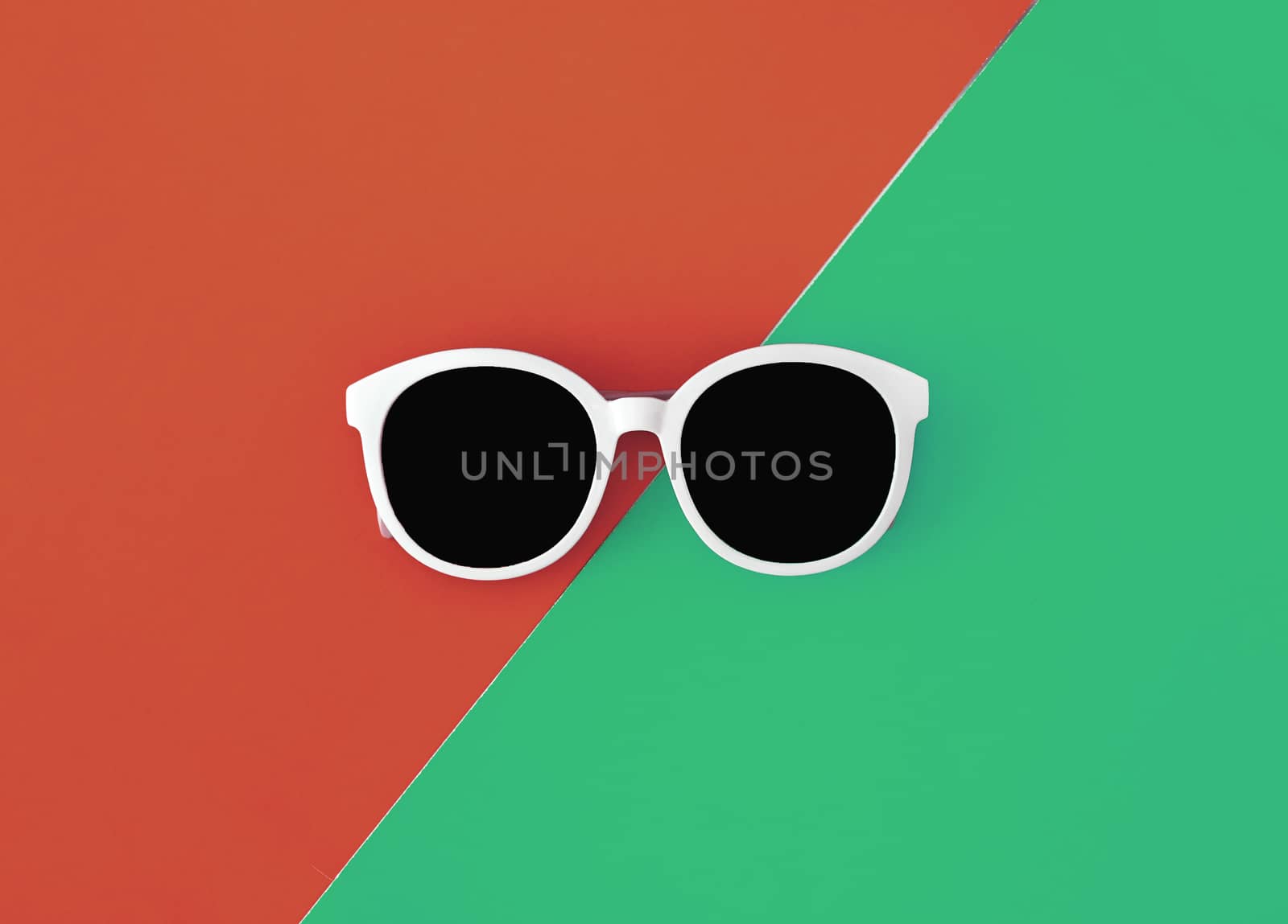 Sunny stylish white sunglasses on a bright green-cyan and red-orange background, top view, isolated. Copy space. Flat lay by Tanacha
