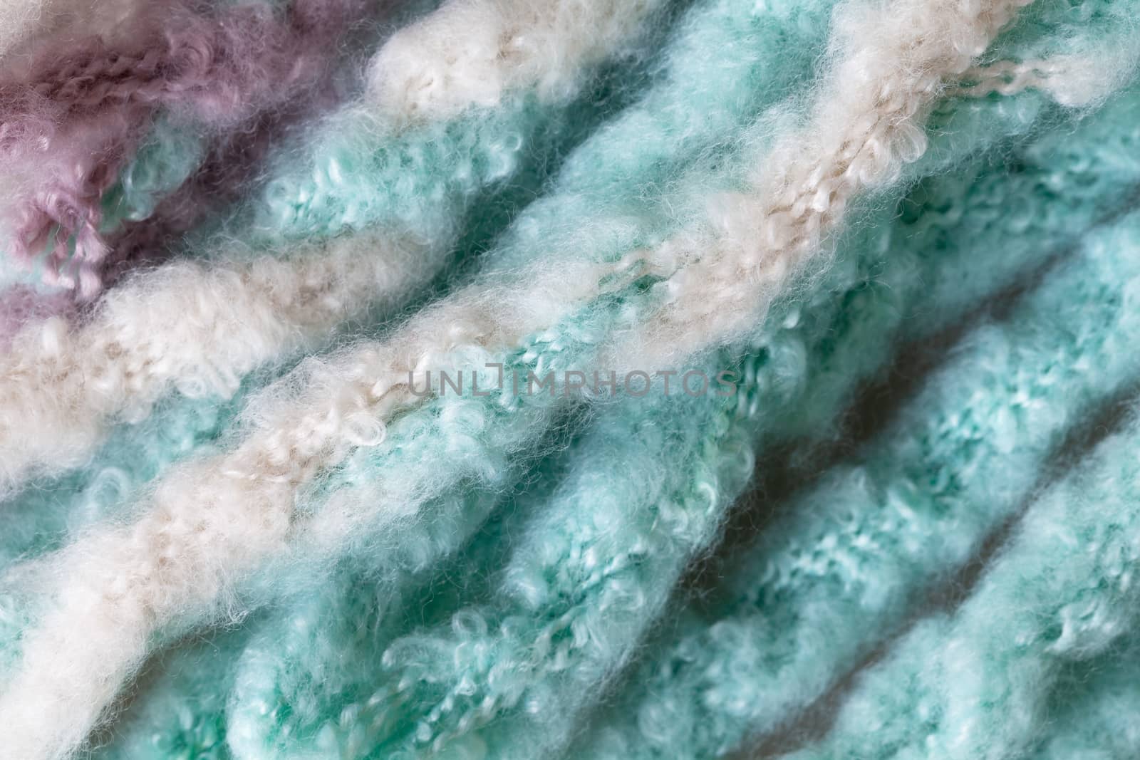 Woolen fluffy threads or tassels from scarf, macro. Soft pastel colors merino wool backdrop, closeup. Autumn and winter flat lay. Scandinavian minimal style.