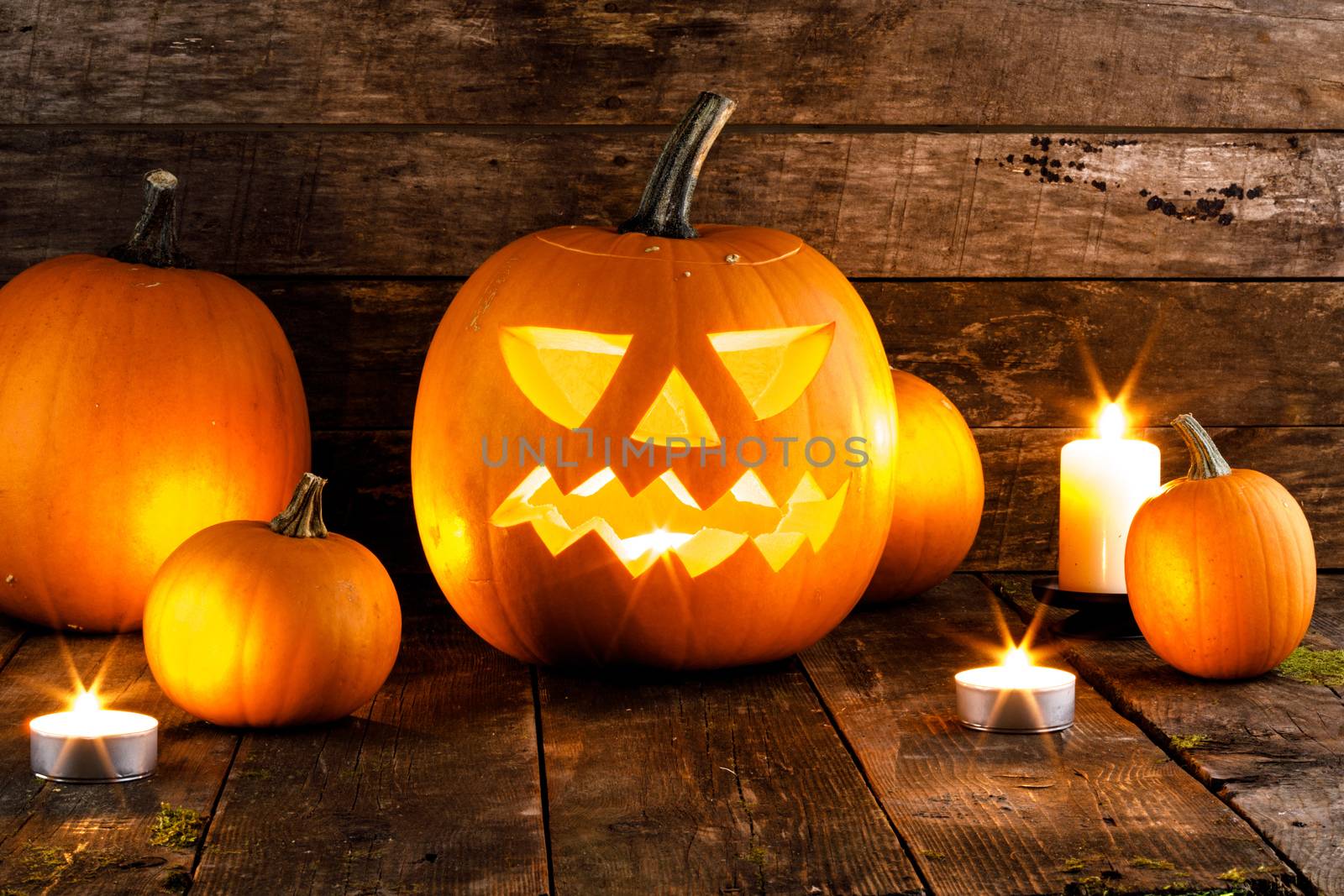 Halloween pumpkin head jack o lantern and candles on wooden background