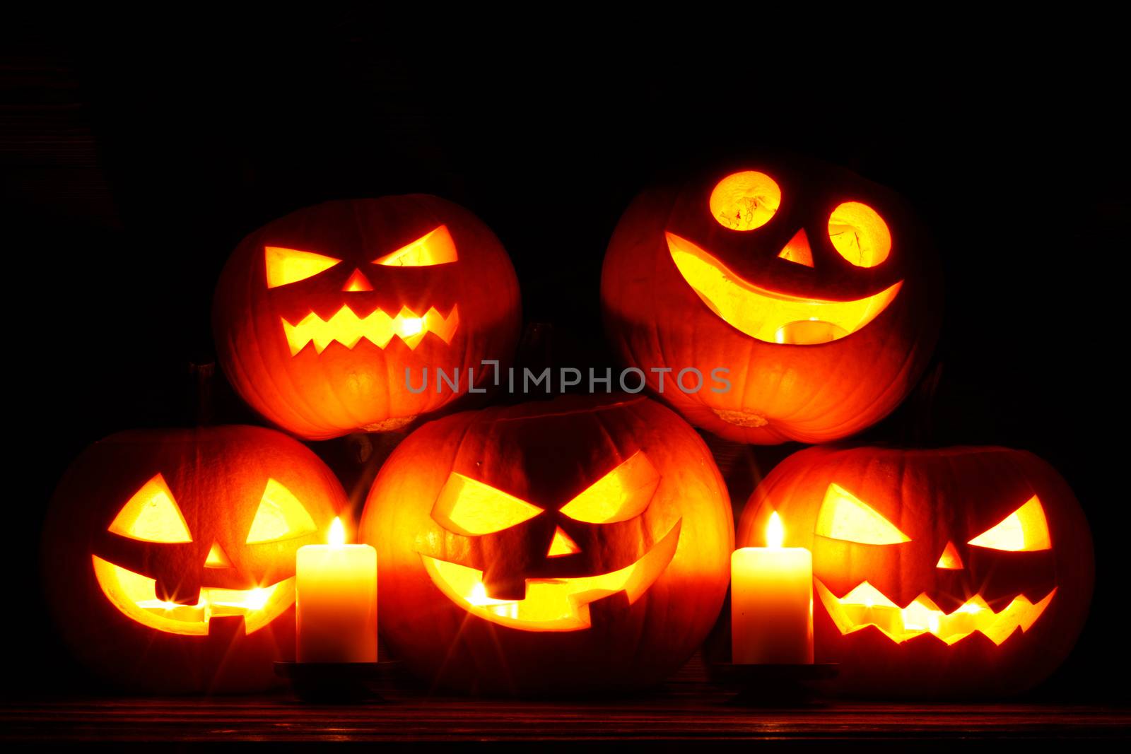Halloween pumpkin head jack o lantern and candles on wooden background