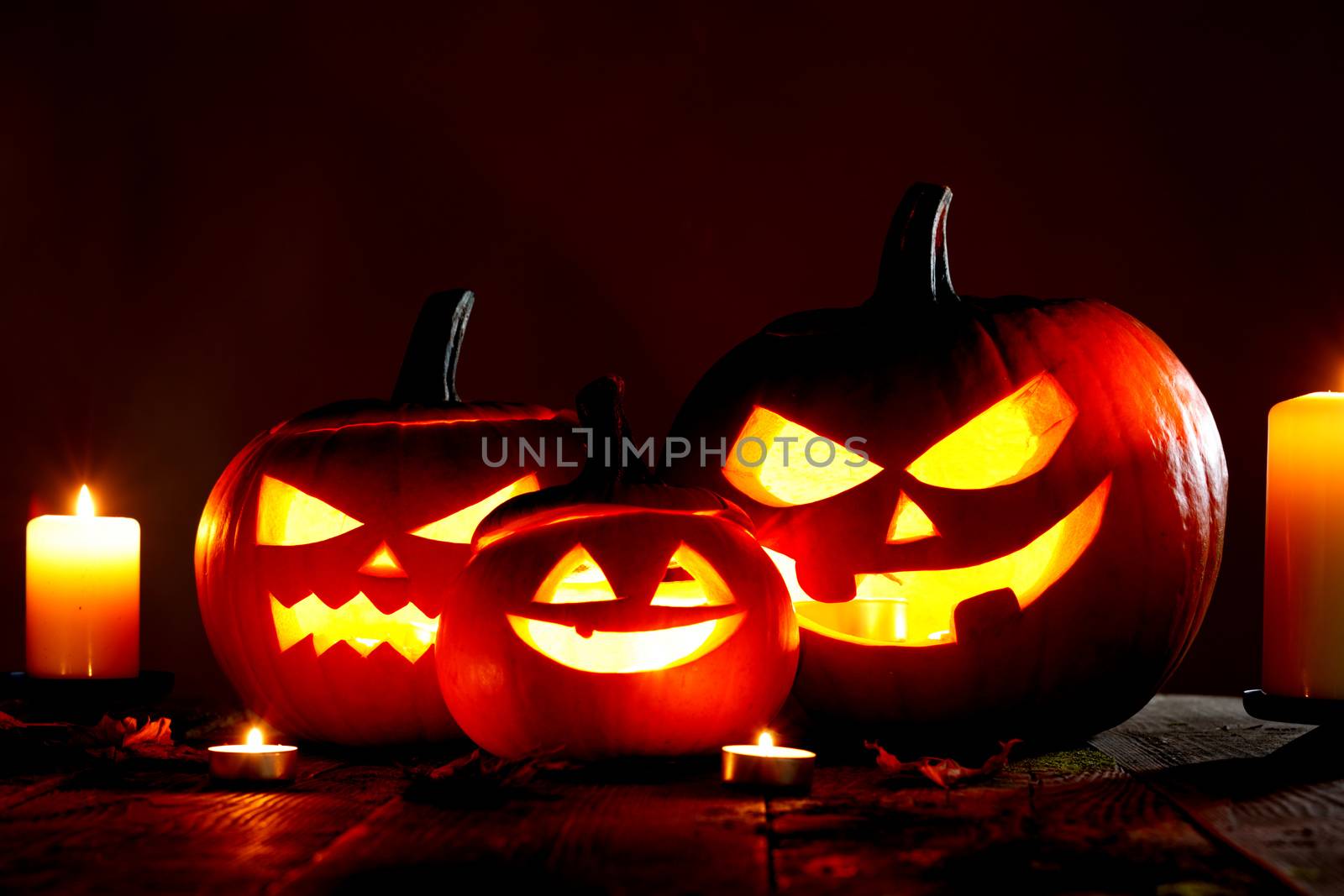 Halloween pumpkin head jack o lantern and candles on gray background