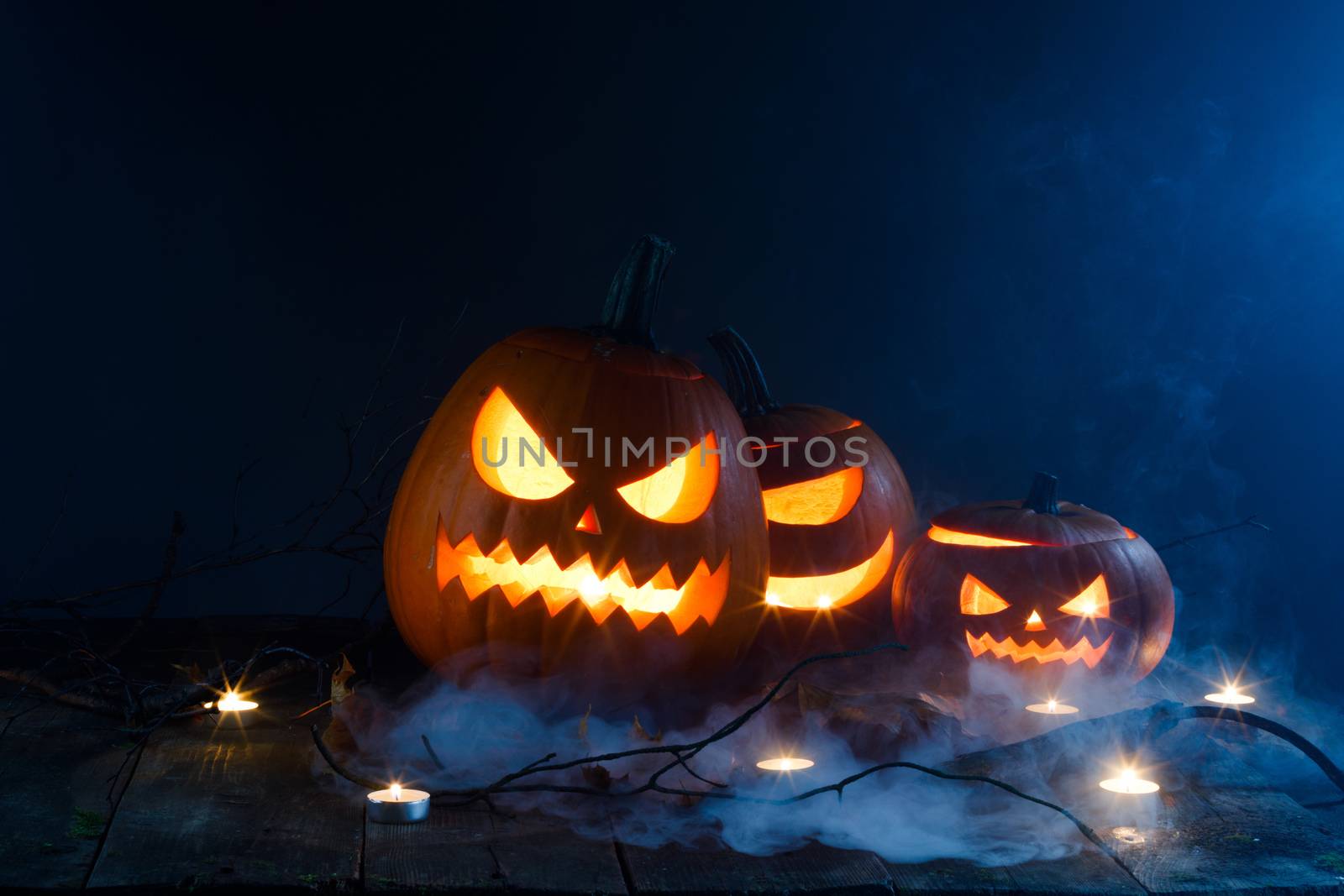 Halloween pumpkin lantern and burning candles in mist at night , copy space